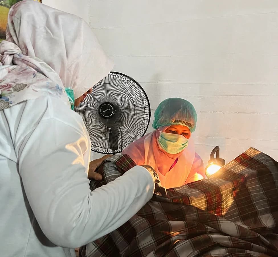 Two health workers performing a VIA exam on a patient