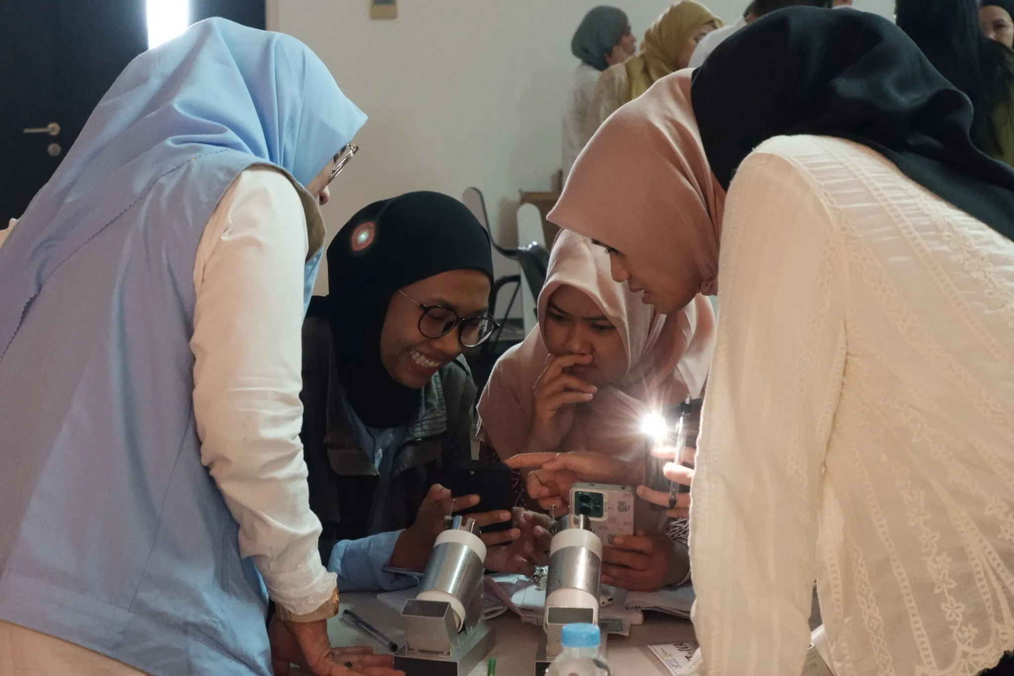 Health workers gathered around smartphones, trying HerLens on training models